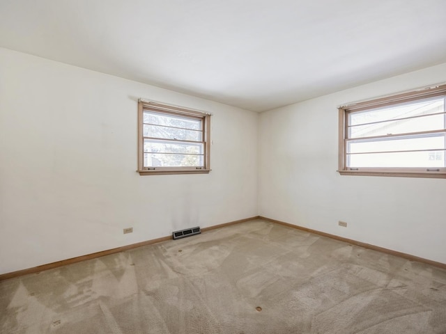 unfurnished room featuring baseboards, carpet, visible vents, and a wealth of natural light