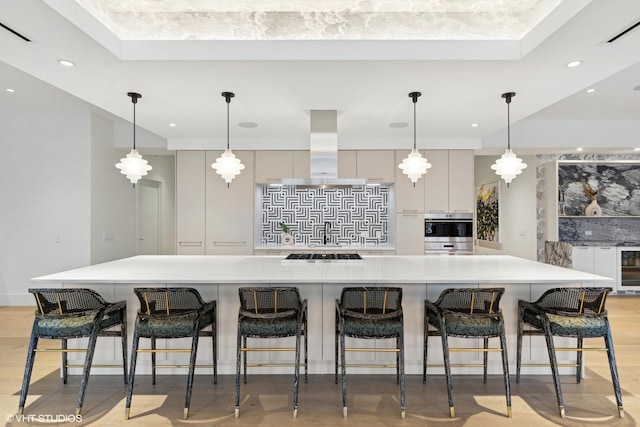 kitchen featuring gray cabinets, light countertops, island range hood, modern cabinets, and a kitchen bar