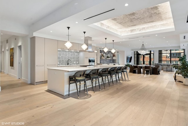 kitchen featuring a spacious island, light countertops, hanging light fixtures, open floor plan, and modern cabinets