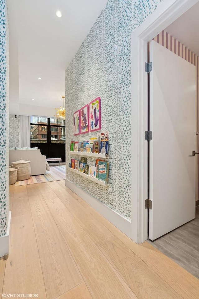 corridor with recessed lighting, wood finished floors, a notable chandelier, and wallpapered walls