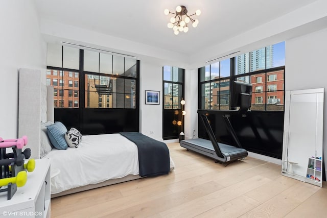 bedroom with a chandelier, a view of city, and light wood-style flooring