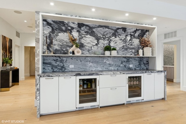 bar featuring light wood-style floors, beverage cooler, and visible vents