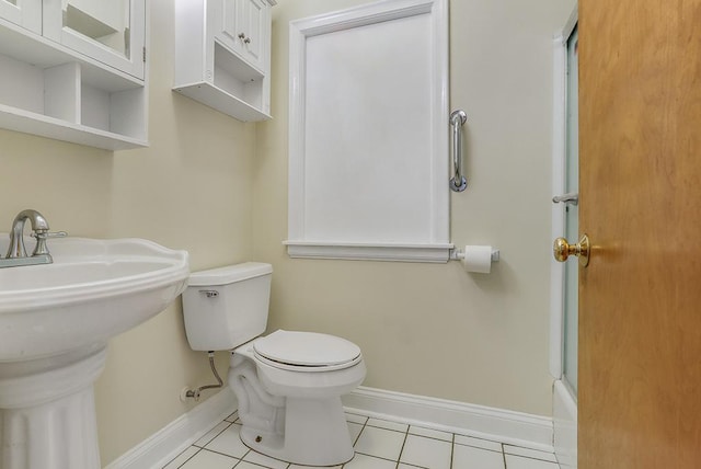 bathroom featuring baseboards, a shower, toilet, tile patterned flooring, and a sink