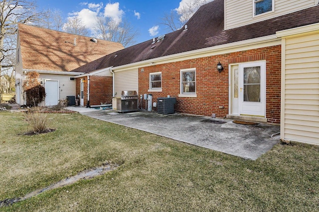 rear view of house with a shingled roof, a patio, a yard, central air condition unit, and brick siding