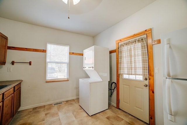 laundry area featuring laundry area, baseboards, stacked washing maching and dryer, and visible vents