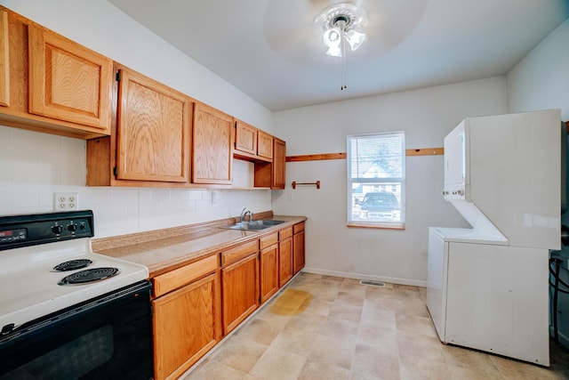 kitchen with tasteful backsplash, electric range oven, stacked washer / drying machine, light countertops, and a sink