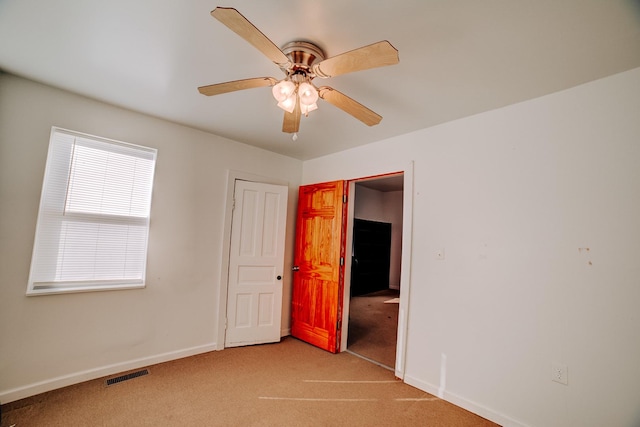 spare room featuring light carpet, baseboards, visible vents, and ceiling fan