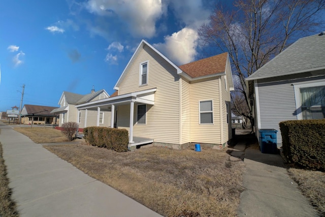 view of home's exterior with a porch and a shingled roof