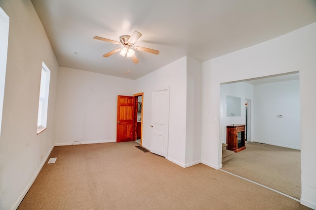 carpeted spare room featuring visible vents, baseboards, and a ceiling fan