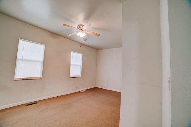 carpeted empty room with visible vents, a ceiling fan, and baseboards