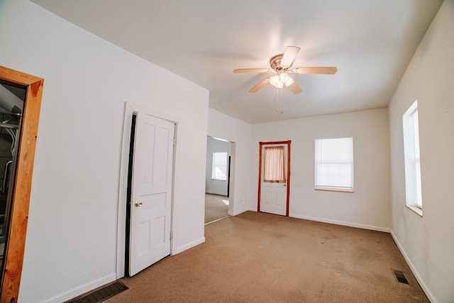 empty room with carpet floors, visible vents, baseboards, and a ceiling fan