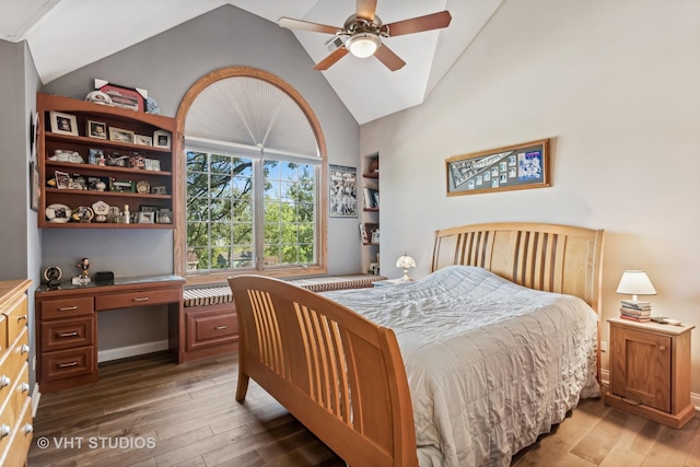 bedroom with dark wood-type flooring, ceiling fan, built in desk, and high vaulted ceiling