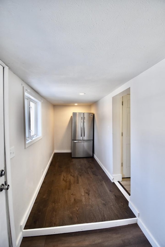 unfurnished room with dark wood-style floors, baseboards, and a textured ceiling