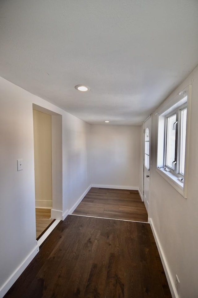 spare room featuring dark wood finished floors and baseboards