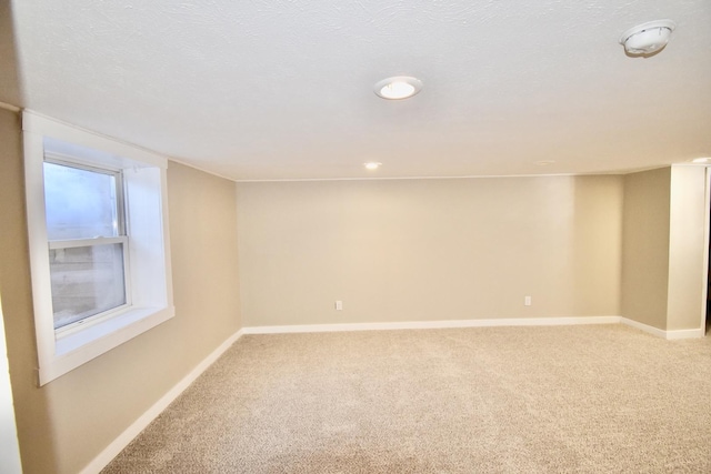 carpeted spare room featuring a textured ceiling and baseboards