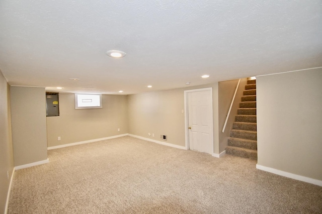 basement with carpet, a textured ceiling, electric panel, baseboards, and stairs