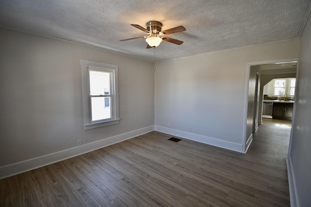 empty room featuring visible vents, dark wood finished floors, baseboards, ceiling fan, and a textured ceiling