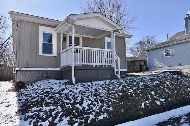 view of front of property with board and batten siding, covered porch, and fence