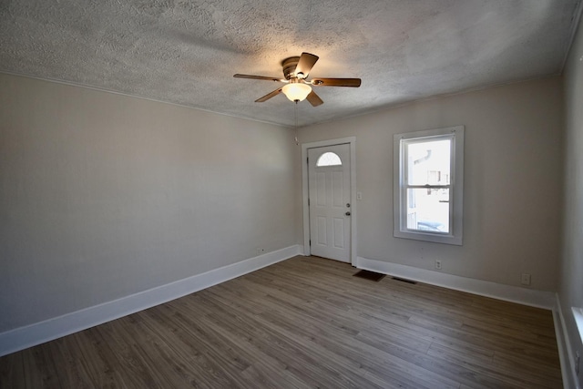 foyer with ceiling fan, a textured ceiling, wood finished floors, visible vents, and baseboards