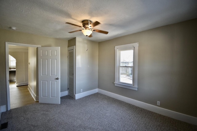 unfurnished bedroom featuring baseboards, a ceiling fan, a textured ceiling, carpet flooring, and a closet