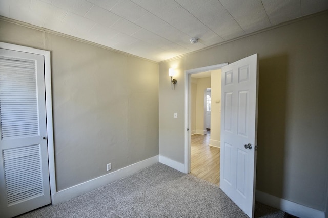 unfurnished bedroom with carpet, baseboards, and crown molding