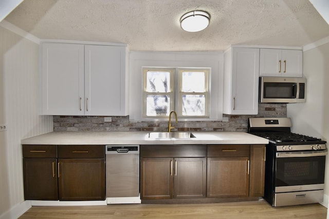 kitchen featuring a sink, dark brown cabinets, stainless steel appliances, and light countertops