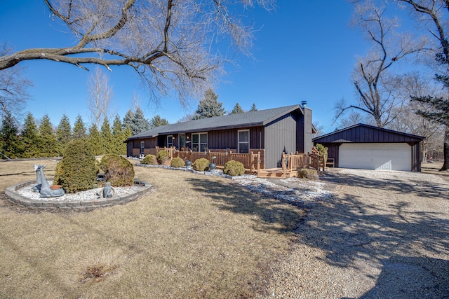 view of front of home featuring a garage, a chimney, a deck, and an outbuilding