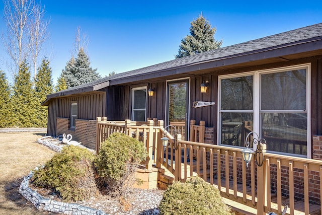 view of front of home with board and batten siding, brick siding, and roof with shingles