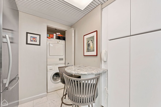 clothes washing area with wood ceiling and stacked washing maching and dryer