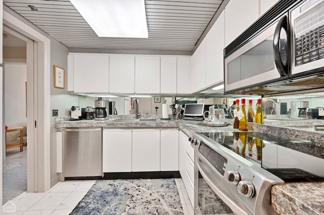 kitchen featuring electric stove, sink, and white cabinets