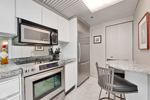 kitchen with white cabinetry, appliances with stainless steel finishes, light stone counters, and wooden ceiling