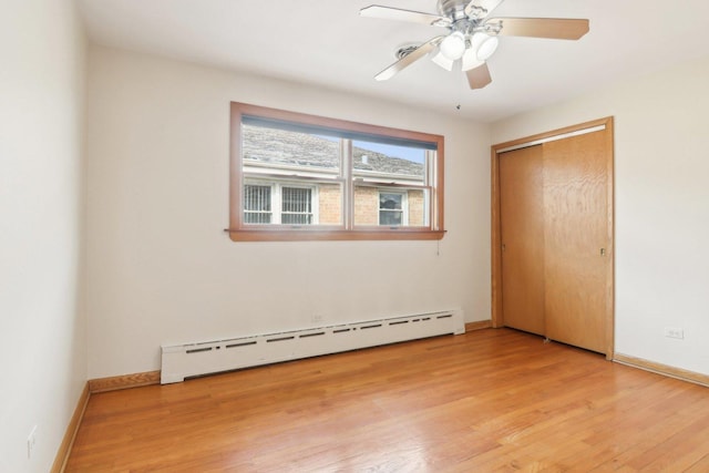 unfurnished bedroom with a baseboard radiator, light wood-style flooring, and baseboards