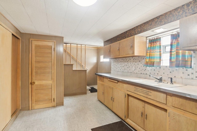 kitchen featuring light floors, light countertops, backsplash, light brown cabinetry, and a sink