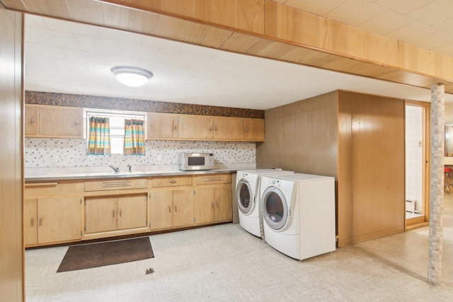 laundry room featuring light floors, washer and clothes dryer, and a sink