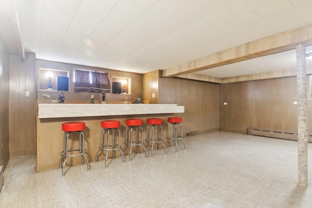 kitchen featuring wooden walls, a breakfast bar area, baseboard heating, and open floor plan