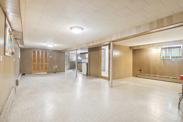 finished basement with a baseboard heating unit, wooden walls, baseboard heating, and tile patterned floors