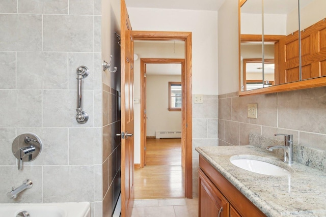 bathroom with shower / washtub combination, a baseboard radiator, tile walls, and vanity