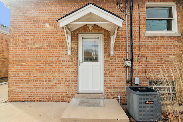 doorway to property featuring brick siding and central air condition unit