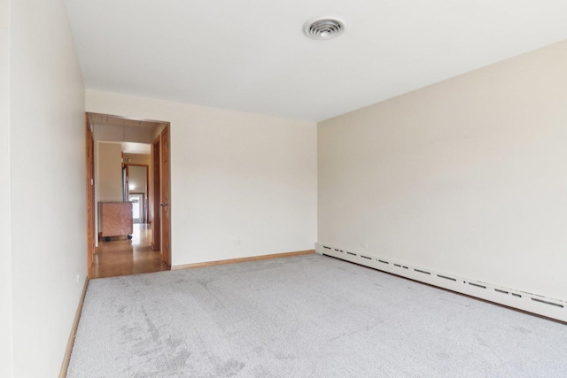 spare room featuring baseboards, a baseboard radiator, visible vents, and carpet flooring