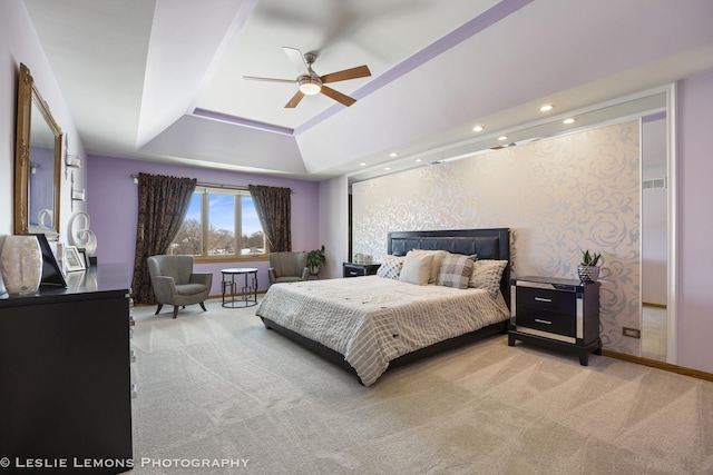 bedroom with a raised ceiling, light colored carpet, and ceiling fan