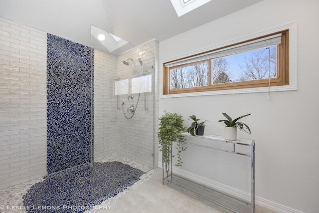 bathroom with tiled shower and vaulted ceiling with skylight