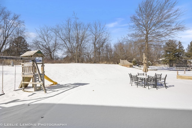 yard layered in snow featuring a playground and a trampoline