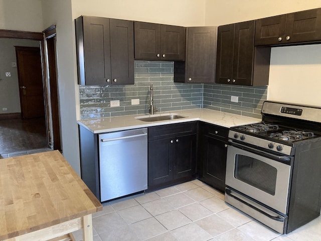 kitchen with sink, backsplash, dark brown cabinets, stainless steel appliances, and light tile patterned flooring