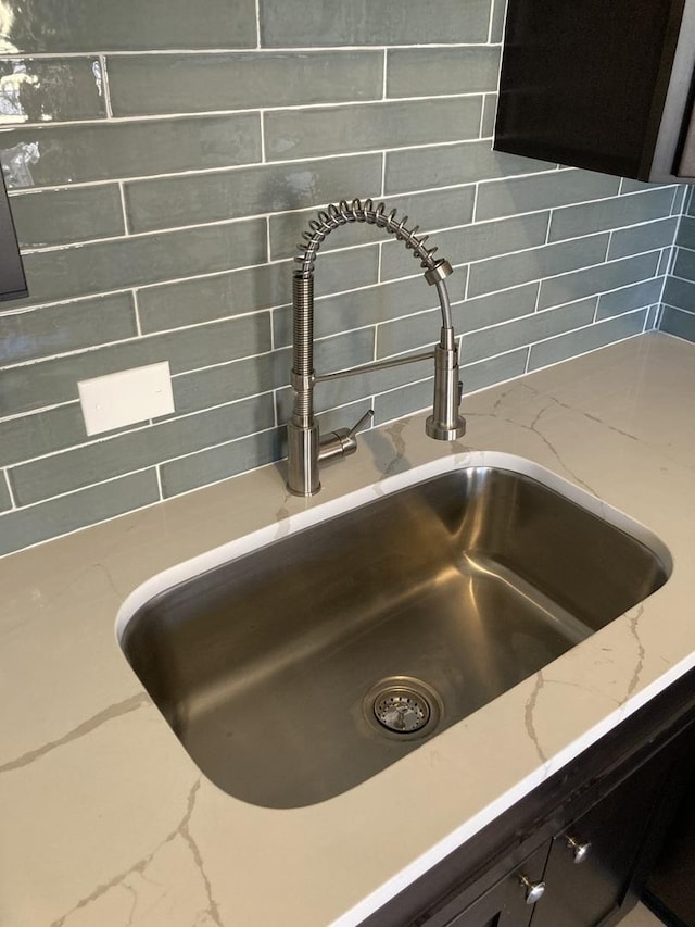 details with sink, backsplash, and light stone counters