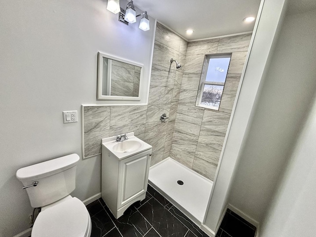 bathroom with vanity, tiled shower, and toilet