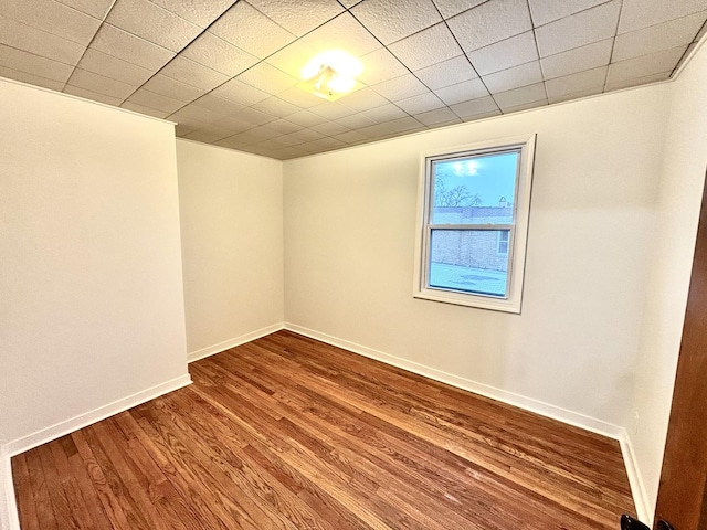 spare room featuring hardwood / wood-style floors and a drop ceiling