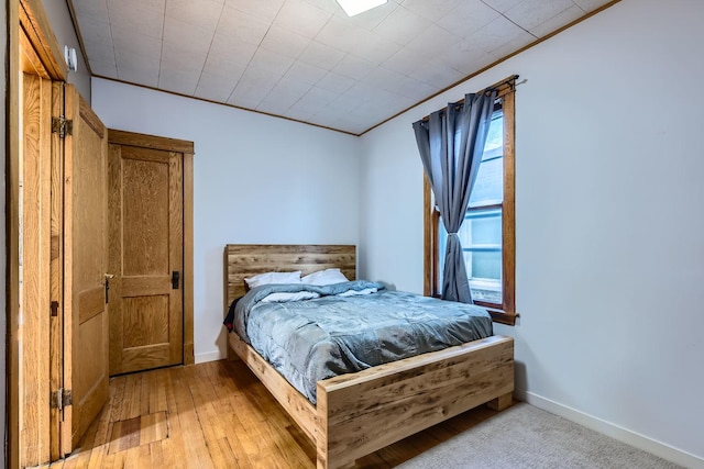 bedroom with crown molding and light hardwood / wood-style floors