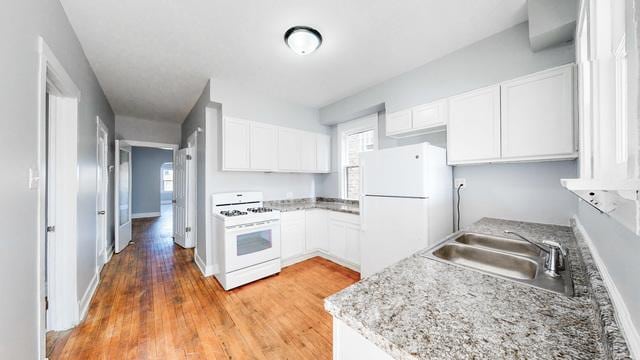 kitchen featuring white appliances, sink, light hardwood / wood-style floors, a healthy amount of sunlight, and white cabinets