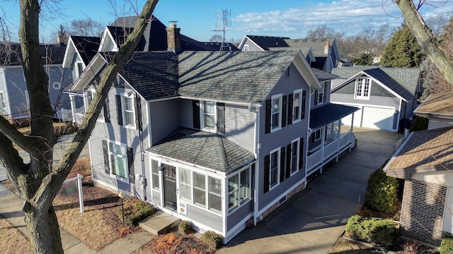 view of side of property featuring a shingled roof, a sunroom, a detached garage, and an outdoor structure