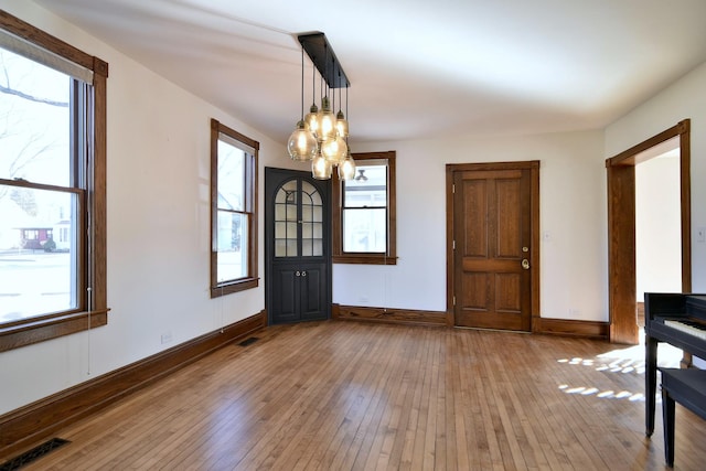 foyer with hardwood / wood-style flooring, baseboards, visible vents, and a chandelier